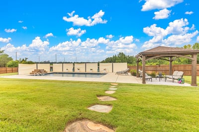 Spacious outdoor area featuring a pool, gazebo, and ample green space, perfect for entertaining.