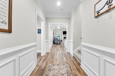 Bright and inviting hallway features modern trim and LVP flooring, leading to a cozy living area.