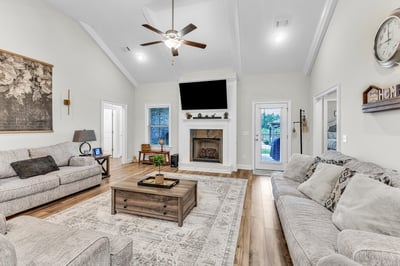 Spacious living area with vaulted ceilings, a cozy fireplace, and abundant natural light throughout.