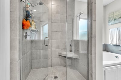 Modern walk-in shower featuring sleek glass doors, ample natural light, and convenient bench seating.