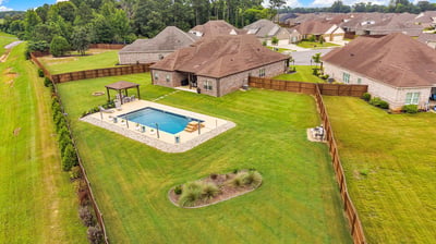 Spacious backyard oasis featuring a pool, pergola, and ample room for outdoor gatherings and activities.