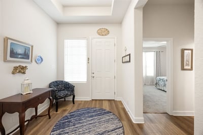 Bright entryway featuring wood-like flooring, unique decor, and convenient access to adjoining spaces.