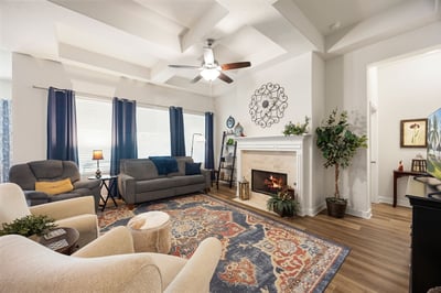 Bright and inviting living room featuring a cozy fireplace, coffered ceilings, and abundant natural light.