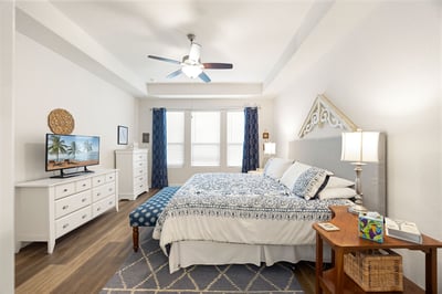 This spacious bedroom features large windows, modern furnishings, and ample natural light for a relaxing retreat.