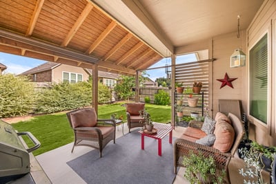 Discover a spacious outdoor patio perfect for gatherings, featuring comfortable seating and lush greenery.