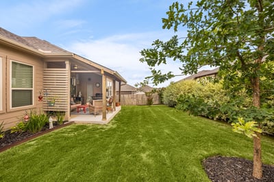 Spacious backyard with a covered patio, perfect for outdoor gatherings and lush landscaping for privacy.