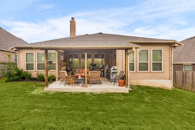 This inviting backyard features a spacious covered patio, perfect for outdoor gatherings and relaxation.