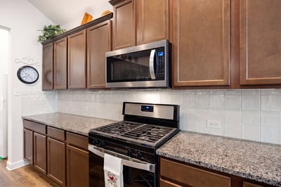 Modern kitchen featuring rich cabinetry, stainless steel appliances, and spacious granite countertops perfect for cooking and entertaining.