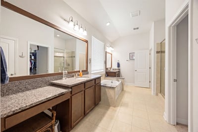Spacious bathroom featuring dual vanities, a soaking tub, and modern fixtures in a well-lit layout.