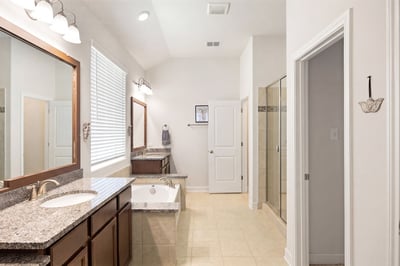 Spacious bathroom featuring dual vanities, a soaking tub, and a large walk-in shower for ultimate convenience.
