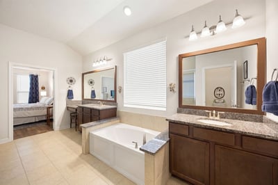 Spacious bathroom featuring dual vanities, a relaxing tub, and abundant natural light throughout.