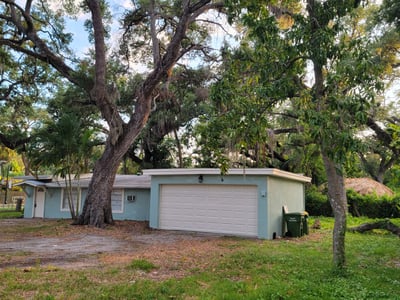 Cozy home surrounded by mature trees, offering potential for outdoor living and personal touches.