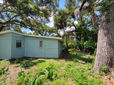 Spacious backyard surrounded by mature trees, offering privacy and potential for outdoor activities or gardening.