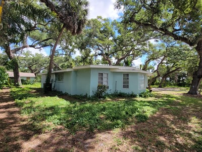 Cozy home surrounded by mature trees, offering a private outdoor space and potential for customization.