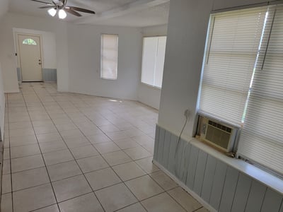 Spacious, well-lit living area featuring tile flooring and large windows for natural light.