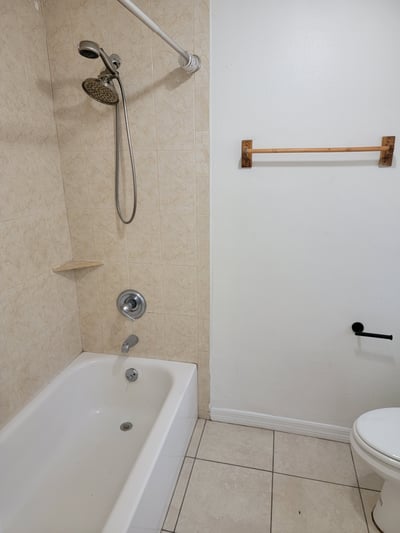 Modern bathroom featuring a tub and shower combination, complemented by clean tile and minimalist fixtures.