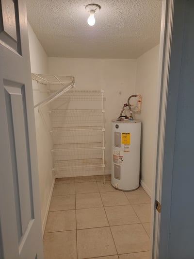 Spacious utility room featuring ample shelving and a water heater, perfect for organized storage solutions.