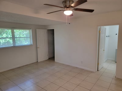 Spacious room featuring ceiling fan, abundant natural light, and easy access to adjoining bathroom and closet.
