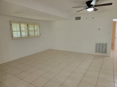 Spacious living area with tiled flooring and plantation shutters, perfect for personalizing your own retreat.