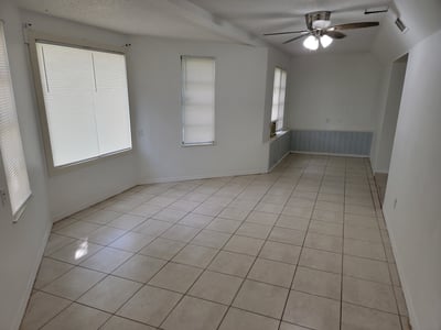 Spacious, open living area features tile flooring and ample natural light from multiple windows.