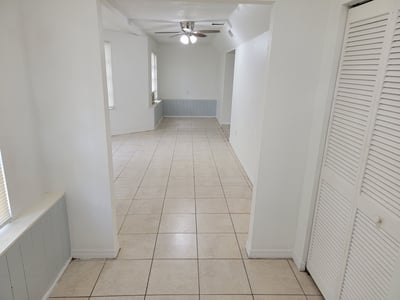 Spacious open-layout living area featuring tiled floors and ample natural light, perfect for versatile living.