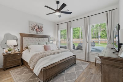 Light filled primary bedroom with tall ceilings and wood-look tile.