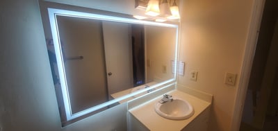 Contemporary bathroom featuring a illuminated mirror and a clean, functional vanity space.