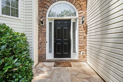 Welcoming black door framed by stone and siding, leading to a inviting entryway.