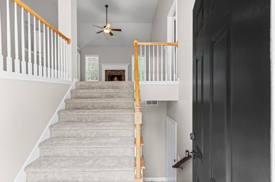 Welcoming foyer features carpeted stairs leading to an inviting living area, perfect for gatherings.