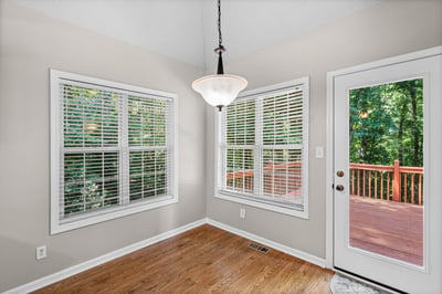 Bright and inviting eat-in kitchen area featuring large windows and access to an outdoor deck.