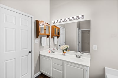 Spacious bathroom featuring dual sinks, ample storage, and a well-lit mirror for daily routines.