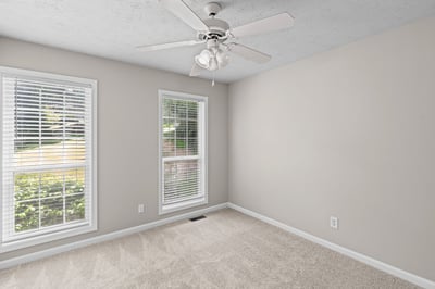 Bright and spacious room featuring large windows, new carpeting, and a ceiling fan for comfort.