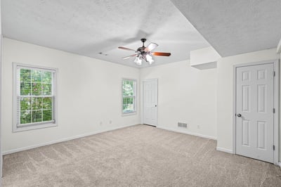 Spacious room featuring natural light, a ceiling fan, and versatile potential for various layouts.