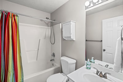 Bright and functional bathroom featuring a colorful shower curtain, modern fixtures, and ample storage space.