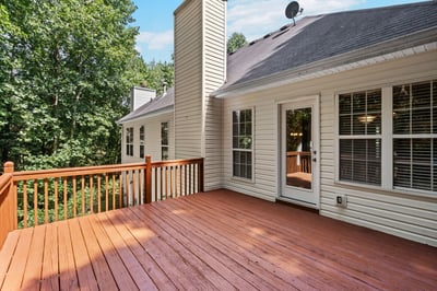 Spacious deck surrounded by lush greenery offers a perfect space for outdoor gatherings and relaxation.