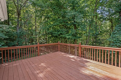 Spacious deck overlooking a lush, wooded area, perfect for outdoor gatherings and relaxation.