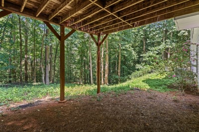 Spacious under-deck area surrounded by lush woods, ideal for outdoor gatherings or storage solutions.
