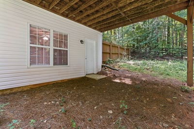 Discover a cozy outdoor space beneath a covered area, perfect for storage or relaxing in nature.