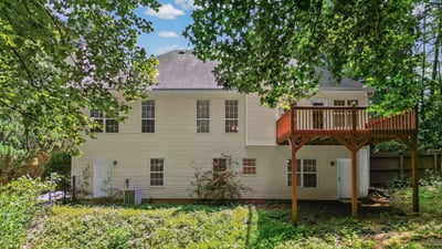 Spacious home with a large deck overlooking a private, wooded backyard, perfect for outdoor gatherings.