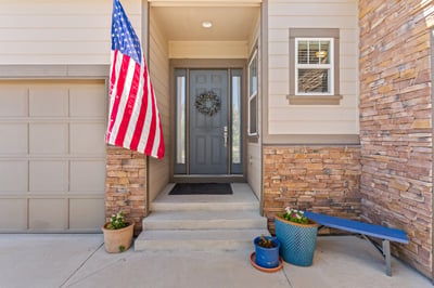 This inviting entrance features unique stone accents and a welcoming American flag, perfect for curb appeal.