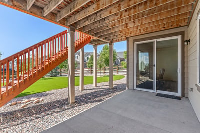 Spacious outdoor area featuring a covered patio and striking wooden staircase, perfect for entertaining or relaxation.