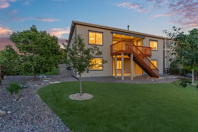 Modern two-story home with expansive windows, a backyard patio, and landscaped grounds, perfect for outdoor gatherings.