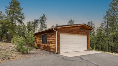 Discover a rustic cabin surrounded by trees, offering a peaceful retreat with modern convenience and garage.