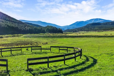 Scenic property featuring a circular fence, surrounded by expansive meadows and breathtaking mountain views.