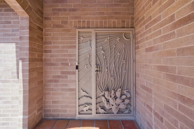 Unique metalwork door creates an inviting entrance, leading into a home filled with character and potential.