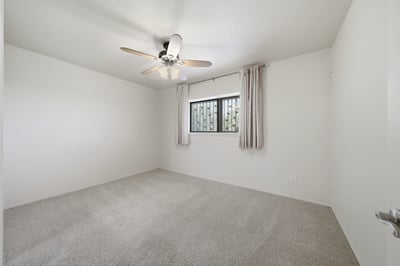 Spacious room featuring a ceiling fan and ample natural light, ready for your personal touch.