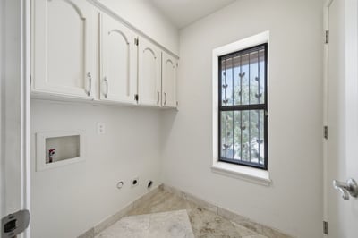 Bright and functional laundry room featuring ample cabinetry and a sizable window for natural light.
