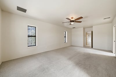 Spacious, light-filled bedroom with neutral tones and ceiling fan, perfect for personalization and comfort.