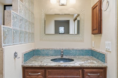 Modern bathroom featuring a striking granite countertop, mosaic tile accents, and ample natural light.