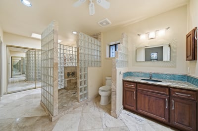 Discover a spacious bathroom featuring a unique glass block shower and modern fixtures for functionality.